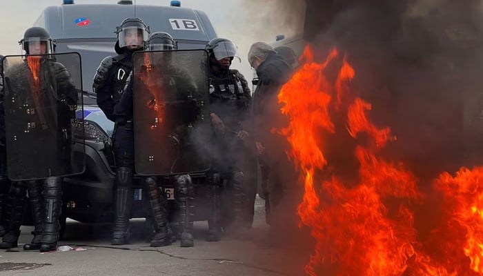 French gendarmes and CRS riot police stand a position near a fire as demonstrators gather on Place de la Concorde near the National Assembly to protest after French Prime Minister Elisabeth Borne delivered a speech to announce to push the pensions reform bill. — Reuters.