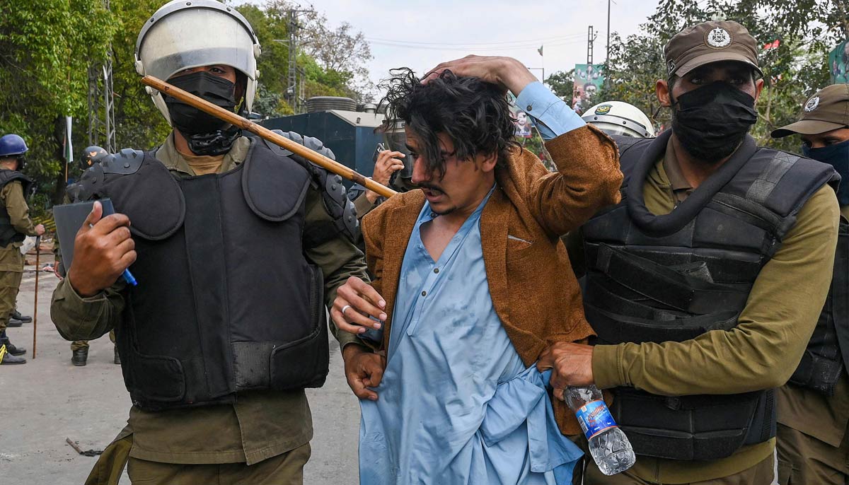 Riot police detain a supporter of Khan outside his residence in Lahore on March 18, 2023. — AFP