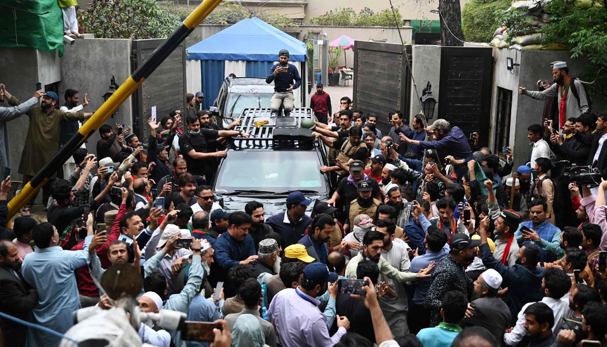 Supporters of Imran Khan gather around his car as he leaves his residence in Lahore on his way to appear in a court in Islamabad on March 18, 2023. — AFP