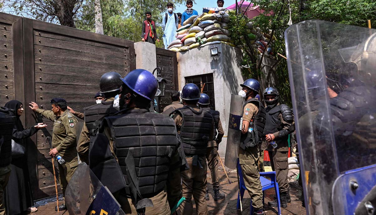 Riot police push a main door to enter the residence the former prime minister Imran Khan, in Lahore on March 18, 2023. — AFP