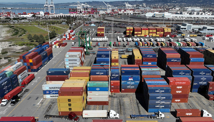 An aerial view, trucks drive by shipping containers at a port. — AFP/File