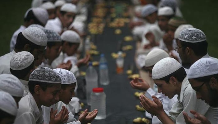 Children offer prayers before having their iftar meal during the holy month of Ramadan at a madrasa. — Reuters