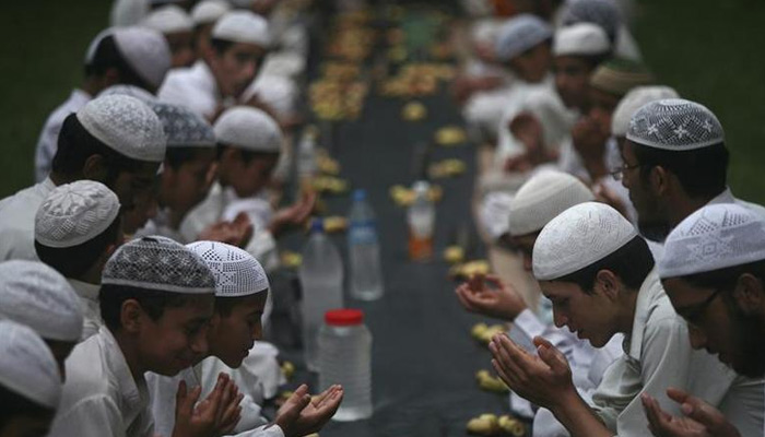 Children offer prayers before having their iftar meal during the holy month of Ramadan at a madrasa. — Reuters