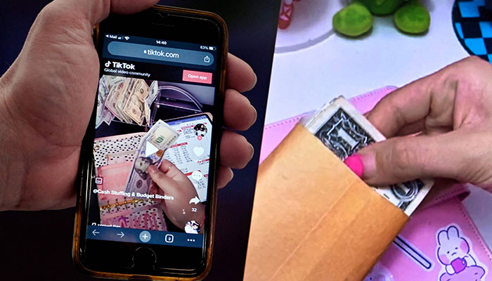 This illustration picture shows the “cash stuffing†TikTok trend, videos where people put cash in envelopes as a budgeting method, displayed on a smartphone in Washington, DC, on March 15, 2023.—AFP