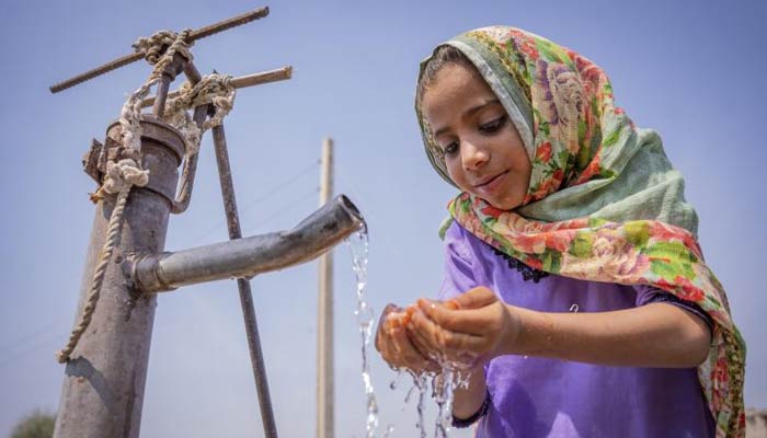 A girl drinks water from a water pump. — Unicef/File