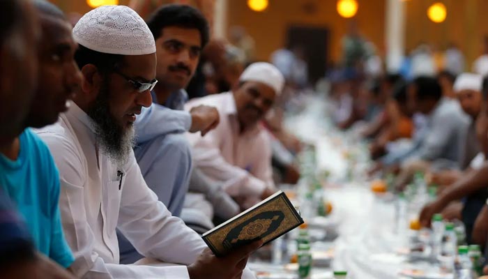 A man reciting Quran as others gather to have their iftar meal on the first day of Ramadan at Prince Turki bin Abdullah mosque in Riyadh on June 29, 2014. — Reuters