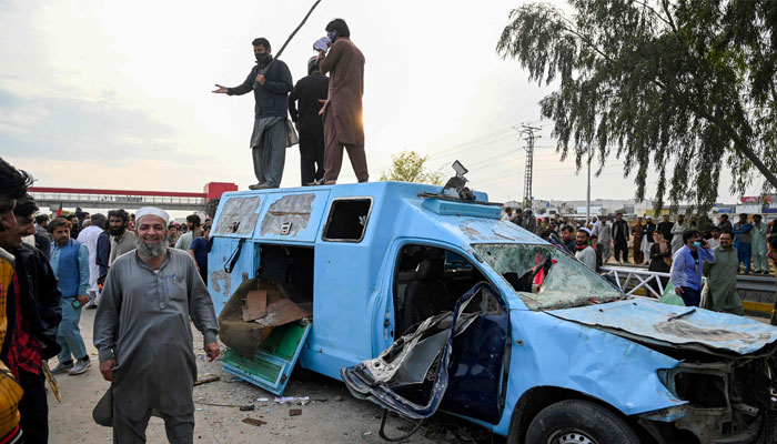 Former prime minister Imran Khans supporters stand atop a damaged police van outside a court in Islamabad on March 18, 2023. AFP