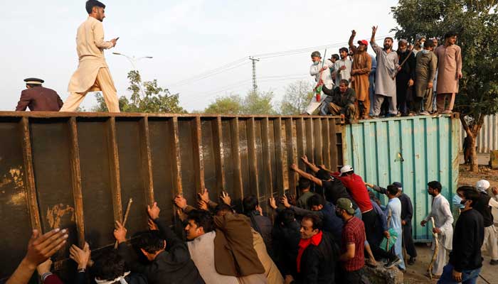 Supporters of PTI chief Imran Khan push a shipping container placed to block the road during a clash outside Federal Judicial Complex in Islamabad, Pakistan March 18, 2023. — Reuters