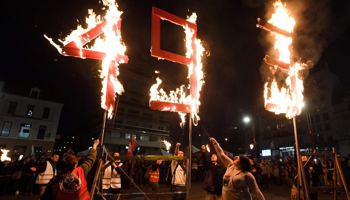 Protesters gather around a fire sculpture that reads 49.3 during a demonstration, a few days after the government pushed a pensions reform through parliament without a vote on March 21, 2023. — AFP