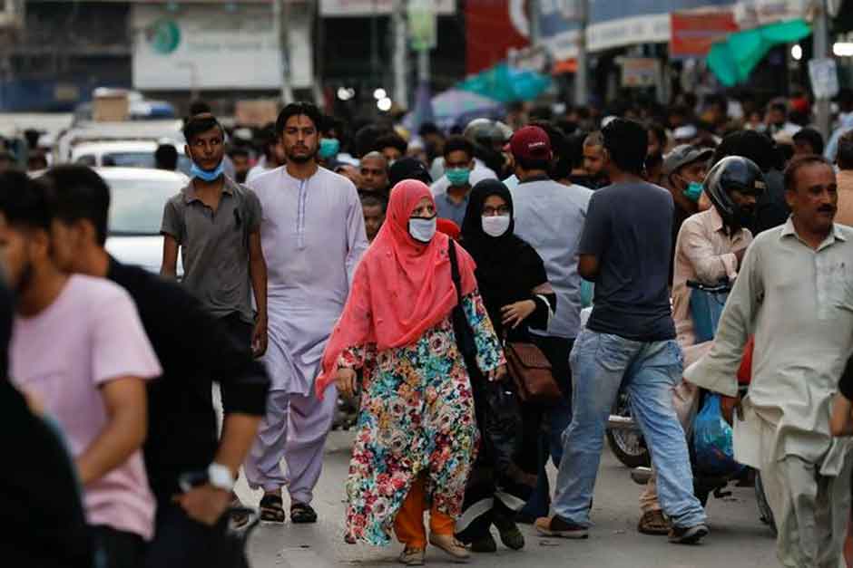 حفاظتی چہرے کے ماسک پہنے خواتین سڑک پر لوگوں کے رش کے درمیان چل رہی ہیں کیونکہ 20 جولائی 2020 کو کراچی، پاکستان میں کورونا وائرس کی بیماری (COVID-19) کا پھیلاؤ جاری ہے۔ – رائٹرز