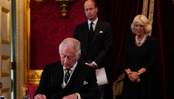Britains King Charles III (seated) signs an oath to uphold the security of the Church of Scotland, as Prince William (C) and Camilla, Queen Consort (R) look on, during a meeting of the Accession Council inside St Jamess Palace in London on September 10, 2022. AFP/File