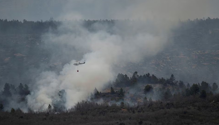 A helicopter drops water on a wildfire in San Agustin, Spain, March 24, 2023. — Reuters