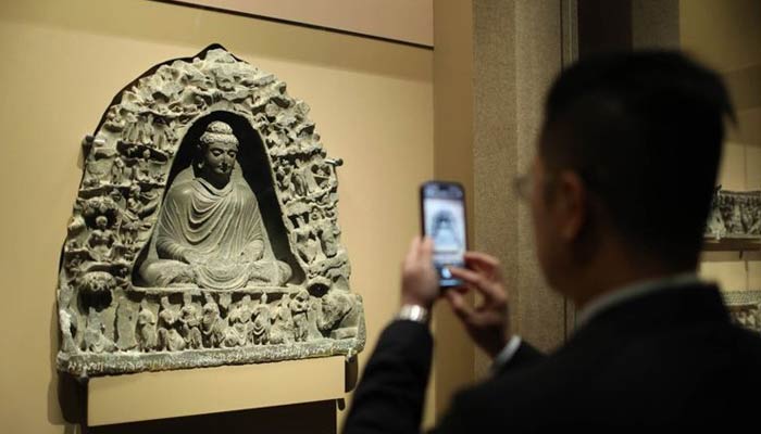 A man takes a picture of a piece at the Gandhara art exhibition in the Wenhua Hall of the Palace Museum in China. —Twitter/@BJNewsWorld