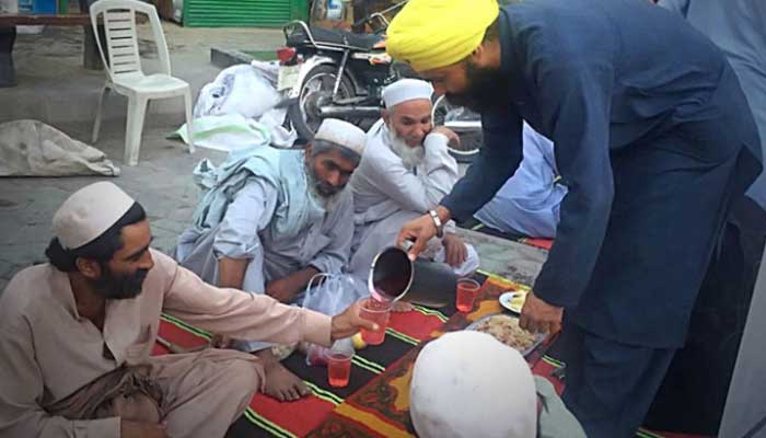 Muslims being served by a member of the Sikh community during iftar time in Peshawar. — APP