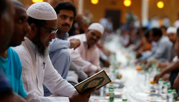 A man reciting the Holy Quran as others gather to have their iftar meal on the first day of Ramadan at Prince Turki bin Abdullah mosque in Riyadh on June 29, 2014. — Reuters