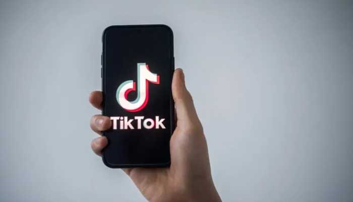 A representational image of a person holding a smartphone with TikTok logo