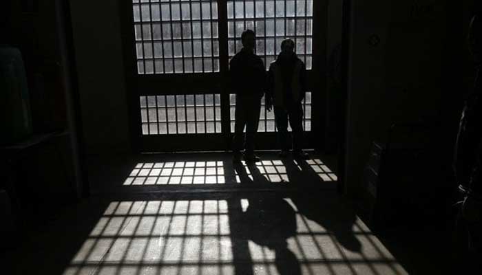 A silhouette of two prisoners standing inside a jail. — Reuters/File