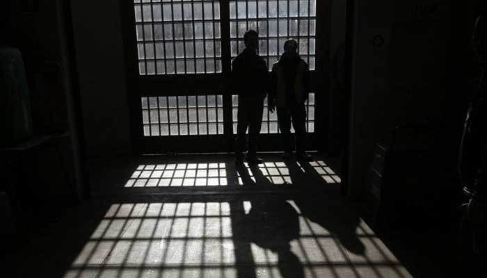 Asilhouette of two prisoners standing inside a jail. — Reuters/File