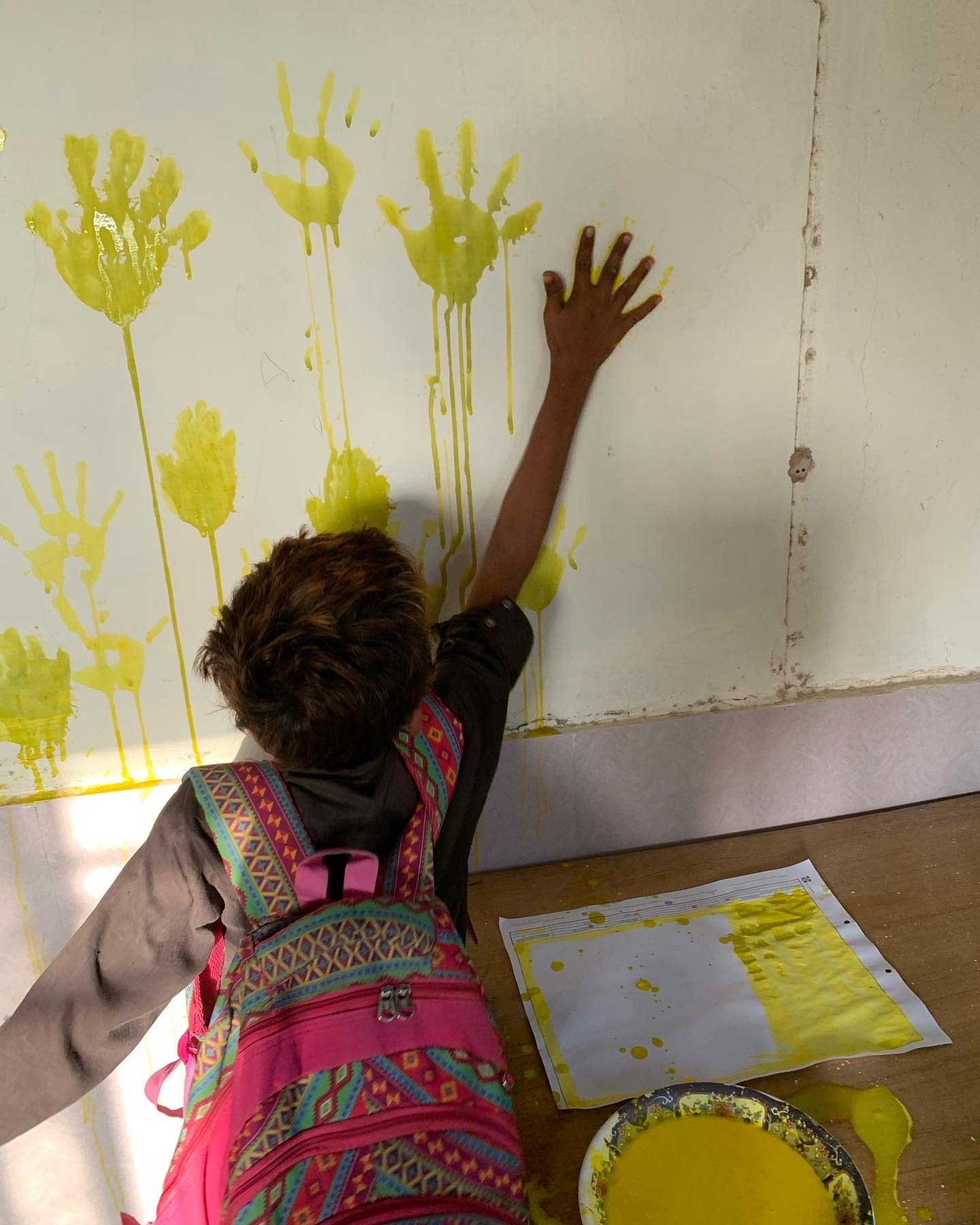 A student paints the schools wall with his handprints. — Photo by Sufiyan Ahamd