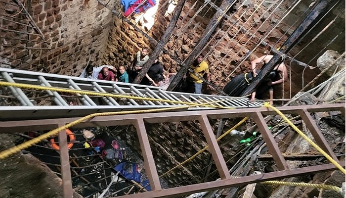 Rescue workers busy pulling the dead and the injured out of the collapsed stepwell. — AFP