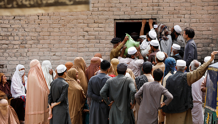 People gather to receive sacks of free flour, at a distribution point in Peshawar, on March 30, 2023. — Reuters