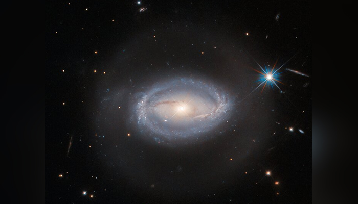 A spiral galaxy surrounded by other distant lightning objects in this image, released on March 27, 2023. — ESA