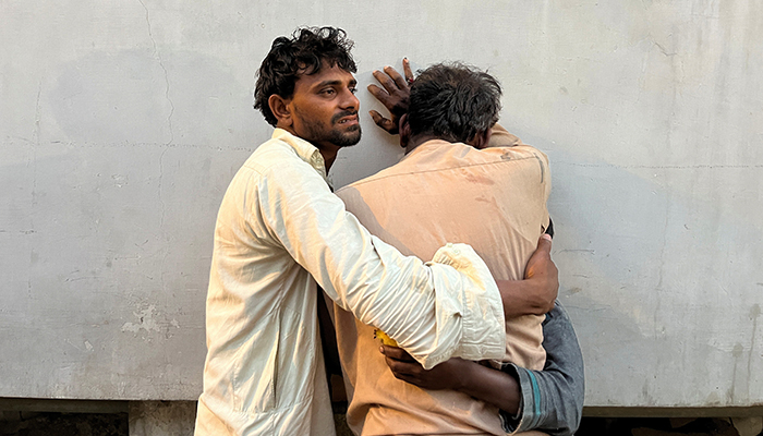Men mourn the death of relative, who was killed along with others in a stampede at a distribution site for food aid in Karachi, on March 31, 2023. — Reuters
