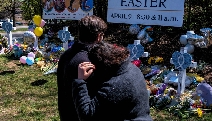 A couple embraces at a makeshift memorial for those killed in a mass shooting at the entrance of The Covenant School on March 29, 2023 in Nashville, Tennessee. — AFP