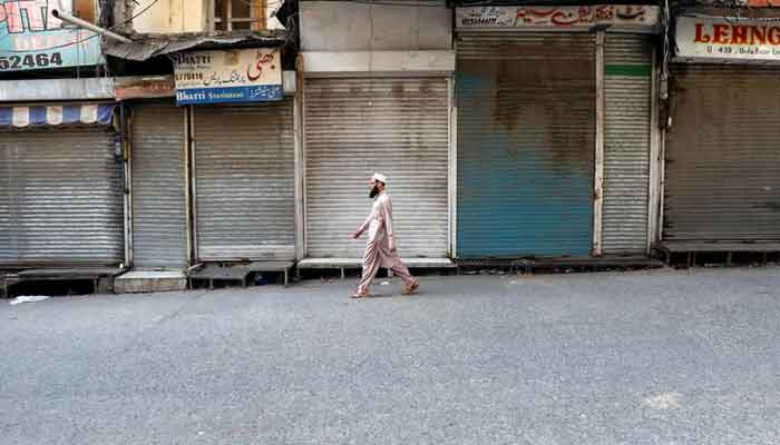 A man walks past closed shops during a countrywide lockdown by traders and business community against imposition of taxes by the government in Rawalpindi, Pakistan on October 29, 2029. — Reuters