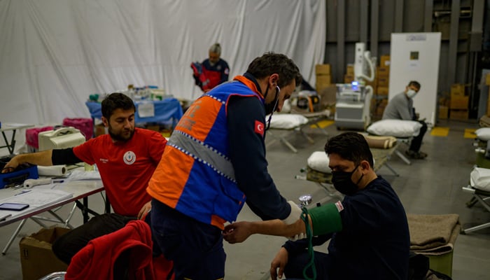 A medic checks a mans blood pressure aboard the Turkish warship TCG Sancaktar. — AFP/File