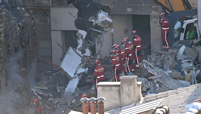 Firefighters stand aside as an excavator clears rubble at ´rue Tivoli´ after a building collapsed in the street, in Marseille, southern France, on April 9, 2023.AFP