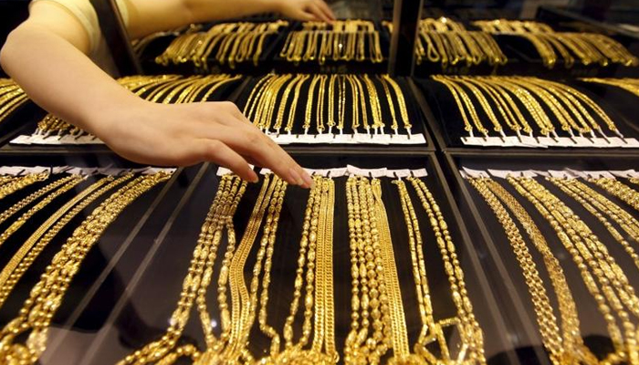 An employee arranges gold jewellery in the counter as her arm is reflected in the mirror at a gold shop in Wuhan, Hubei province, in August 25, 2011. — Reuters