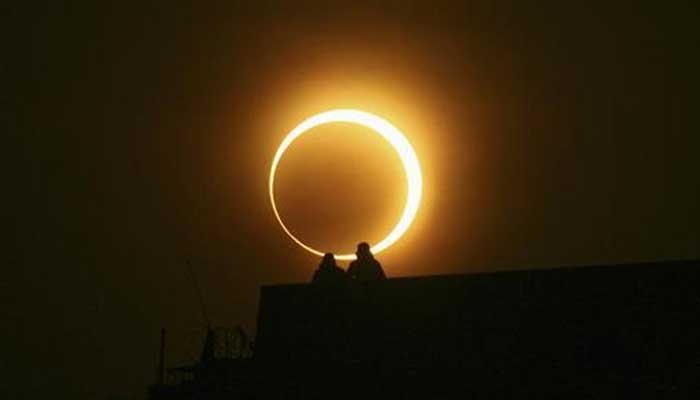 Two men sit on a bridge to watch solar eclipse of the millennium in Zhengzhou, Henan province, January 15, 2010. — AFP
