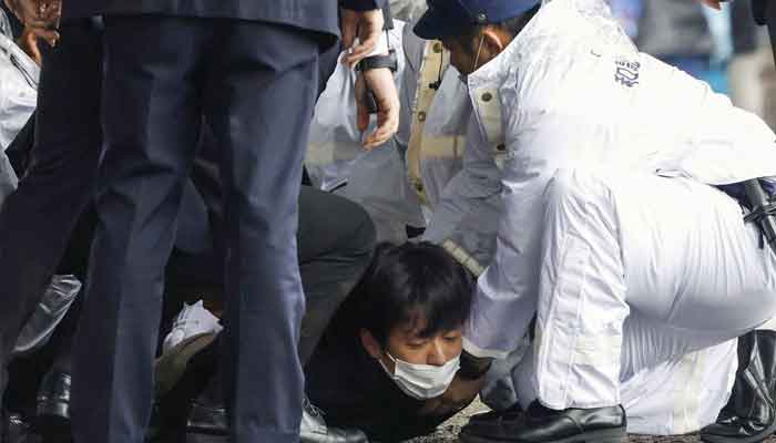 A man, believed to be a suspect who threw a pipe-like object near Japanese Prime Minister Fumio Kishida during his outdoor speech, is held by police officers at Saikazaki fishing port in Wakayama, Wakayama Prefecture, south-western Japan April 15, 2023, in this photo released by Kyodo. —Reuters