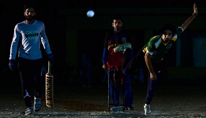 A player delivers a ball during a nighttime cricket tournament during the month of Ramadan in Karachi on April 7, 2023. — AFP
