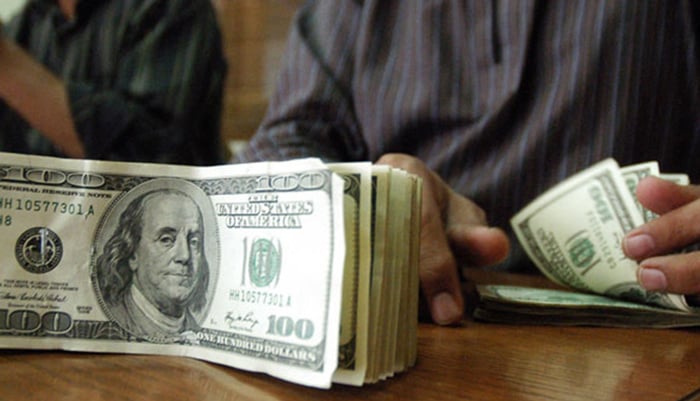 A currency dealer counts USD notes at an exchange in Pakistan. — AFP/File