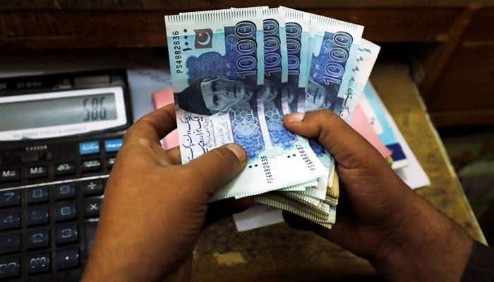 A trader counts Pakistani rupee notes at a currency exchange booth in Peshawar, on December 3, 2018. — Reuters