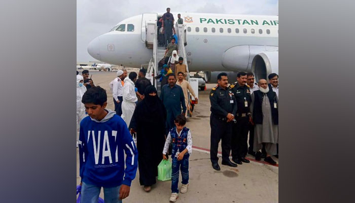 پھنسے ہوئے پاکستانی کراچی پہنچنے کے بعد طیارے سے باہر نکل رہے ہیں۔  -FO