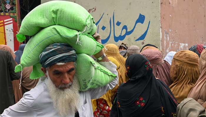 A man leaves after collecting free bags of flour from a government distribution point in Peshawar on March 29, 2023. — AFP