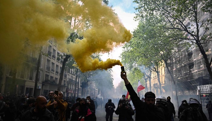 A protester brandishes a yellow smoke grenade as he takes part in a demonstration on May Day. — AFP