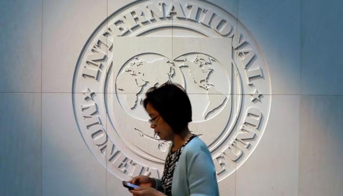 A woman walks past the International Monetary Fund (IMF) logo at its headquarters in Washington, US, May 10, 2018. — Reuters
