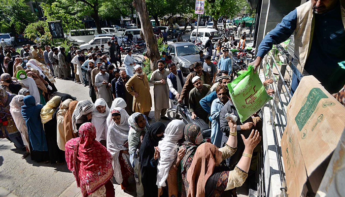 People stand in a queue to purchase flour bags at a market in Islamabad on March 27, 2023. — APP/File