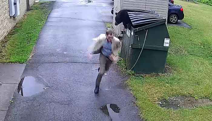 The picture shows Principal James Marsh running away from black bear. — Facebook screenshot/@Nicholas County Board of Education