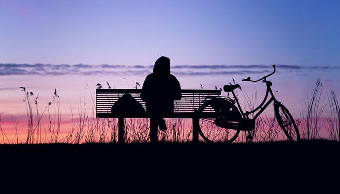 A representational image of a person sitting alone, with a bicycle. — Pixabay/File