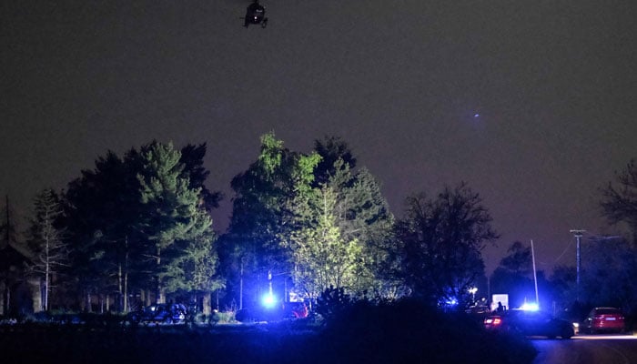 A helicopter hovers as policemen block the road near the village of Malo Orasje, just outside the town of Mladenovac, about 60 kilometres (37 miles) south of Serbia´s capital Belgrade, on May 05, 2023. — AFP