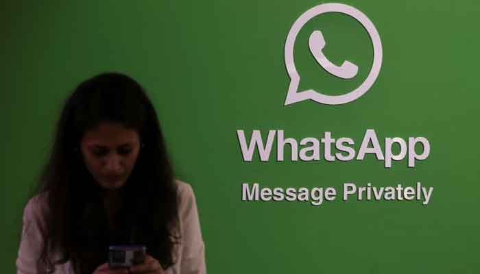 A woman uses her phone next to a logo of the WhatsApp application during Global Fintech Fest in Mumbai, India September 20, 2022. — Reuters