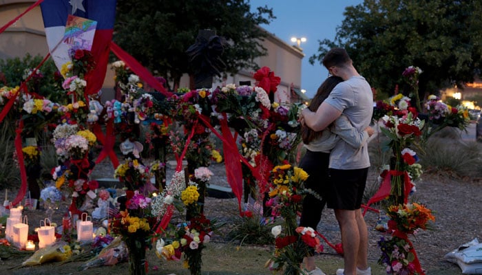 People hug as they visit the memorial next to the Allen Premium Outlets on May 7, 2023, in Allen, Texas. — AFP