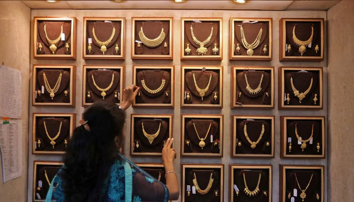 A saleswoman shows a gold necklace to a customer at a jewellery showroom. — Reuters/File
