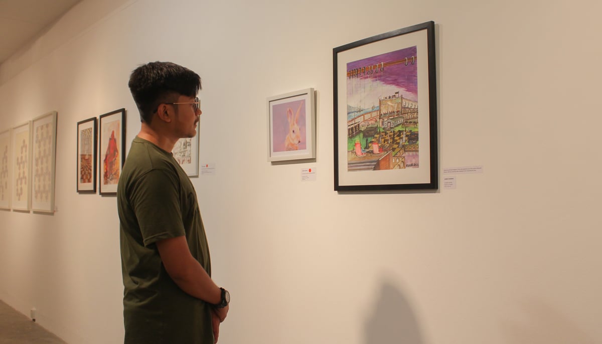 Saad Ahmed Rabbani looks at his fathers artwork at the IVS art gallery. — Photo by Hassaan Ahmed