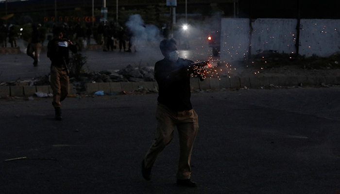 A police officer fires tear gas to disperse the supporters of former prime minister Imran Khan, during a protest against his arrest, in Karachi, May 9, 2023. — Reuters